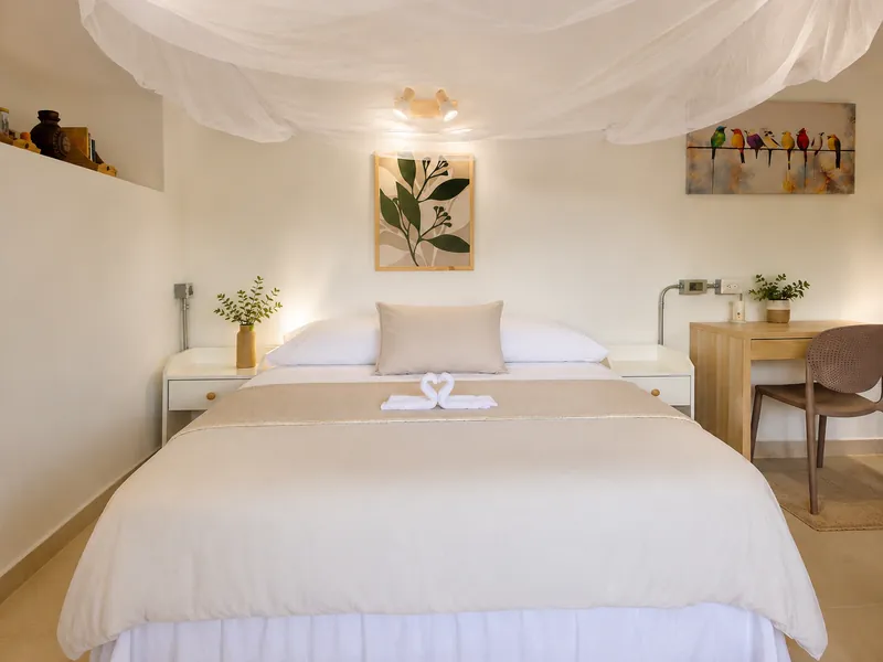 Cama queen con mosquitero de tul y toallas en forma de cisnes