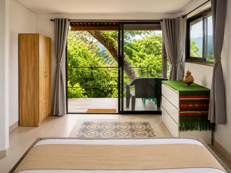 Habitación con puerta-ventana abierta hacia la terraza y los árboles